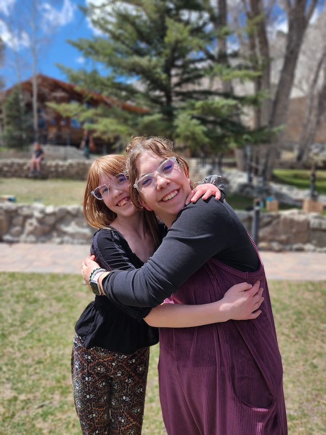 A woman and adolescent girl hugging and smiling for the camera