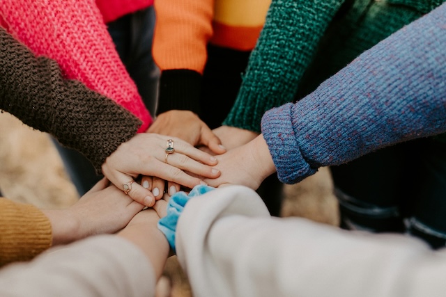 A group of women gathered in a circle with their hands being held together in the middle