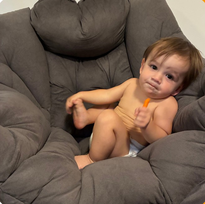 Smiling baby sitting in a big gray chair