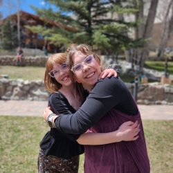 A woman and adolescent girl hugging and smiling for the camera